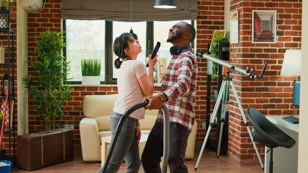 Diverse husband and wife dancing and sweeping floors