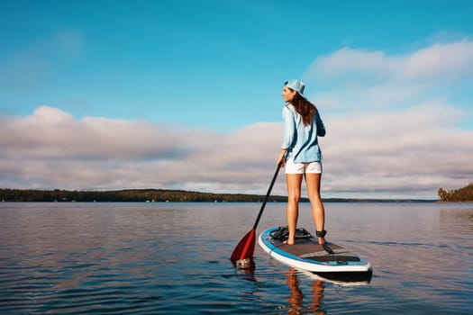 The beauty out here is breathtaking. a young woman paddle boarding on a lake.