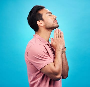 Man is praying, religion and faith with worship to God, belief and spirituality isolated on blue background. Male person in prayer, Christian and gratitude with mindfulness and peace in studio