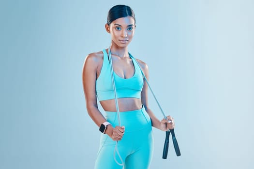 Fitness, skipping rope and mockup with a sports woman in studio on a blue background for health or wellness. Exercise, mindset and space with a young female athlete training for cardio or endurance