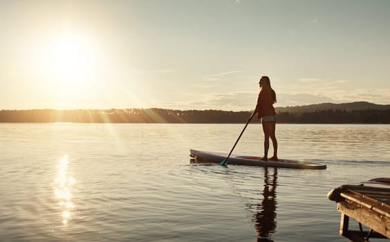 If in doubt, paddle out. an attractive young woman paddle boarding on a lake.