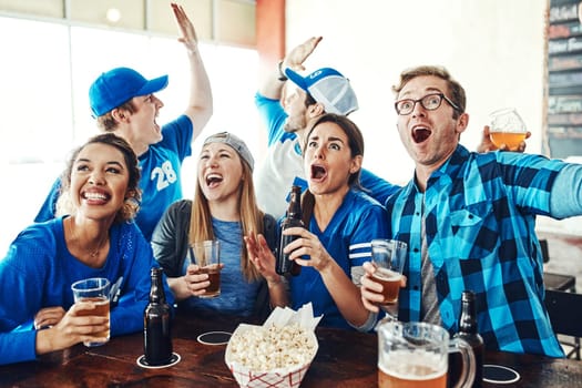 Loud and proud sports fans. a group of friends cheering while watching a sports game at a bar.
