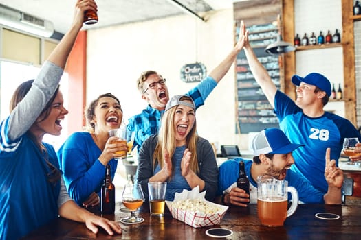 Theyve got sports fever. a group of friends cheering while watching a sports game at a bar.