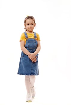 Full length vertical portrait of Caucasian lovely little preschooler girl smiling looking at camera, white background