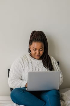 African american young woman using laptop on bed - technologies and communication and social network concept