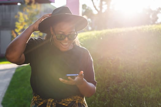 Close up portrait of happy african american young woman browsing social networks in city - generation z and urban concept