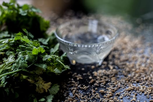 Exfoliating skincare face mask on a black-colored surface consisting of some coriander leaves and egg white along with some oats.