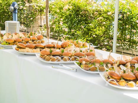 Banquet table with snacks food on plates hamburger party dinner table - buffet table after wedding ceremony