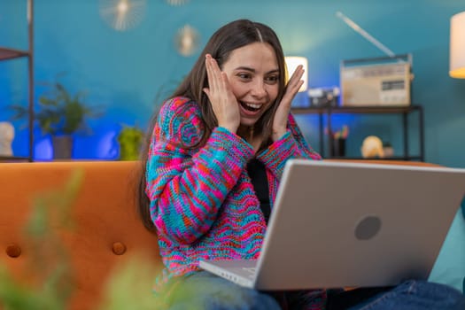 Amazed young woman use laptop computer, receive good news message, shocked by victory, celebrate win