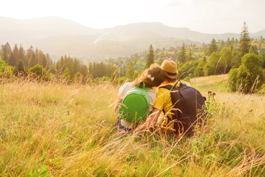 Happy young couple sitting on mountain couple looking at view mountain love couple nature vacation green travel love vacation summer mountain travel rest people nature travel love together. Back view