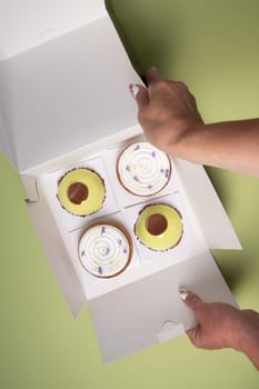 female hands open a box with different cakes dessert home delivery