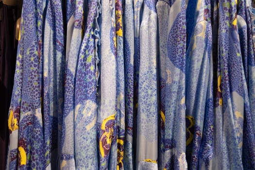 blue with yellow flowers summer blouses on a hanger in the store, bright clothes