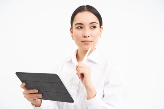 Corporate asian woman, manager using digital tablet, working on gadget, checking charts, company statistics, standing over white background