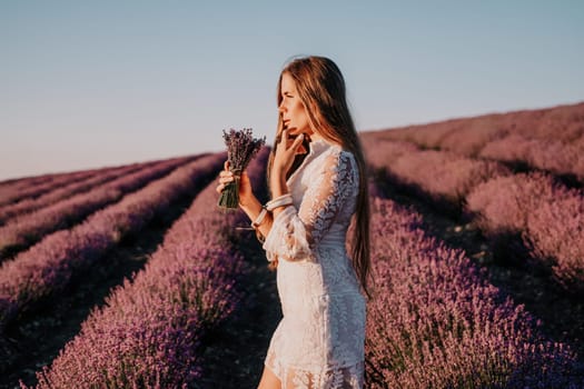 Woman lavender field. Happy carefree woman in a white dress walking in a lavender field and smelling a lavender bouquet on sunset. Ideal for warm and inspirational concepts in wanderlust and travel.