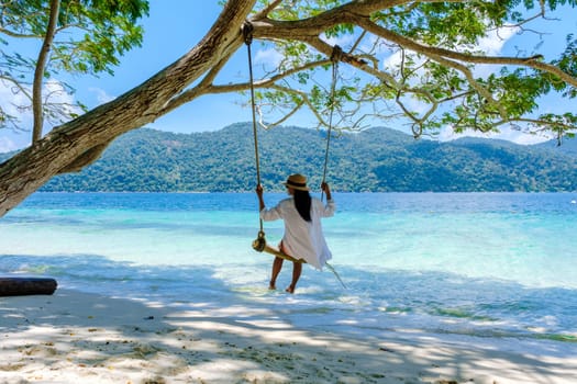 woman at a rope swing on the beach of Koh Lipe Island Southern Thailand
