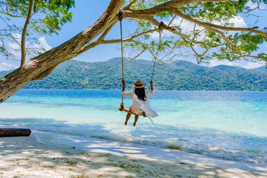 woman at a rope swing on the beach of Koh Lipe Island Southern Thailand