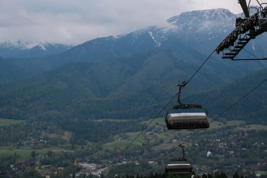 Ski Lift snowy mountain autumn forest with chair lift At The Ski Resort in Zakopane Poland. Holidays Vacation sport and outdoor activities tourism cable car empty seat grass field in green forest on hill