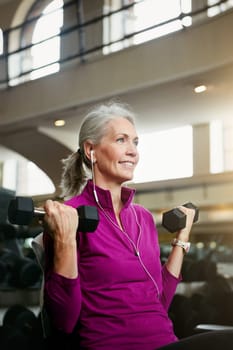 When I lift weights, I also lift my spirits. Portrait of a happy senior woman working out with weights at the gym.