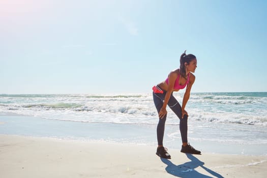 Taking the scenic route to fitness. an attractive young woman working out on the beach.