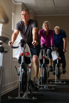 Fit is not a destination, it is a journey. a group of seniors having a spinning class at the gym.