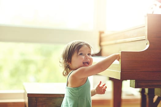 Mini maestro in the making. an adorable little girl playing on the piano at home.