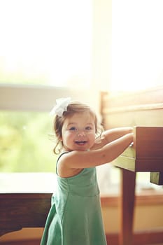 Youre just in time for my solo performance. Portrait of an adorable little girl playing on a piano the home.