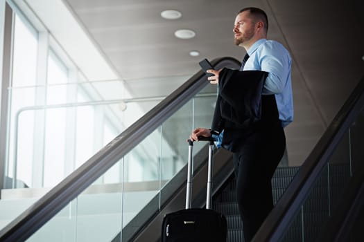 The business travel expert. a businessman traveling down an escalator in an airport