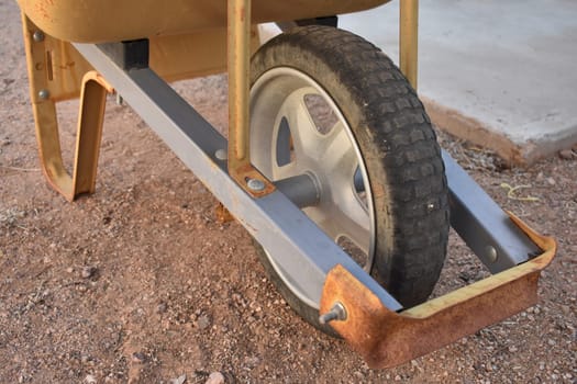 Wheel on Bottom of Orange Wheelbarrow on Dirt Ground