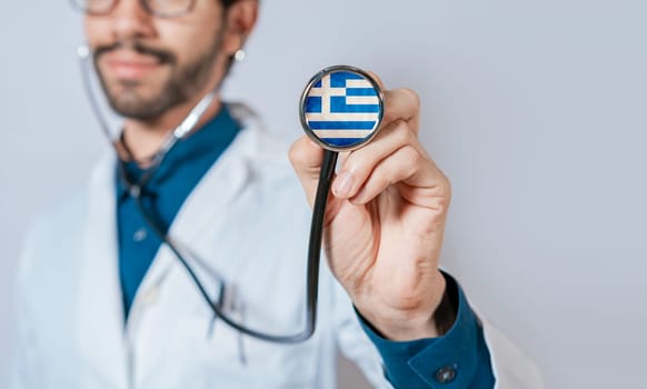 Greece flag on stethoscope. Doctor holding stethoscope with greece flag. Male doctor showing stethoscope with flag of greece