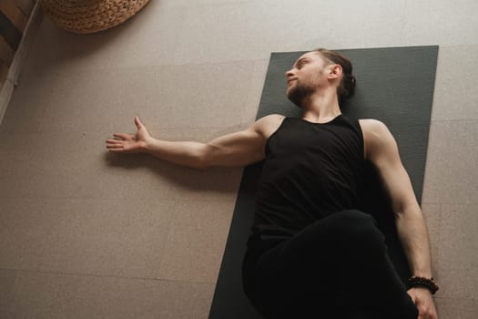 A man performing gymnastic exercises on a yoga mat at home