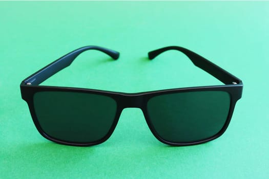 Black sunglasses on a green background.