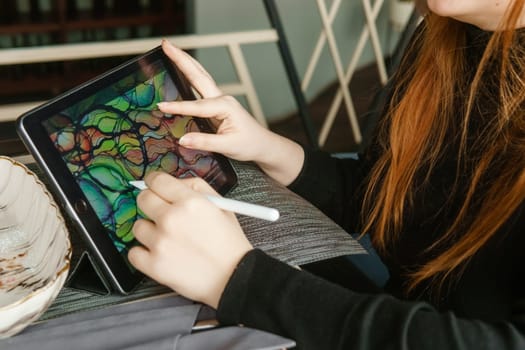 TVER, RUSSIA - FEBRUARY 11, 2023: A young woman draws neurography with a stylus on a tablet. Psychological session to remove restrictions, art therapy