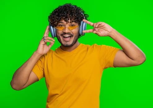 Indian happy man in headphones listening music dancing disco having fun relaxing on christmas party
