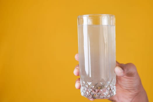 holding dirty glass of water on yellow background