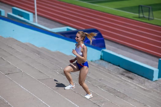 Young caucasian woman running on stadium stairs outdoors.