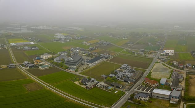 Aerial view of buildings and roads under low fog in Japanese countryside