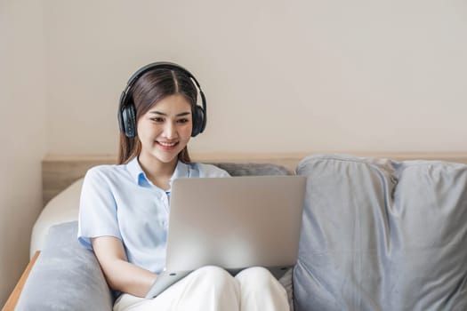 young student wearing headphones studies online,conversation via video call,distance learning on the sofa in the house..