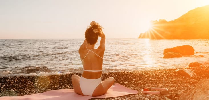 Woman sea yoga. Happy woman in white swimsuit and boho style braclets practicing outdoors on yoga mat by sea on sunset. Women yoga fitness routine. Healthy lifestyle, harmony and meditation