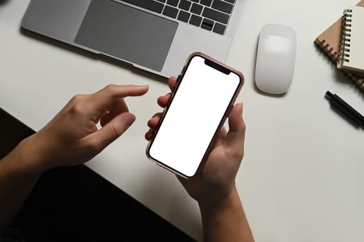 Closeup view of man using smartphone at working desk. Blank screen for your advertising text message