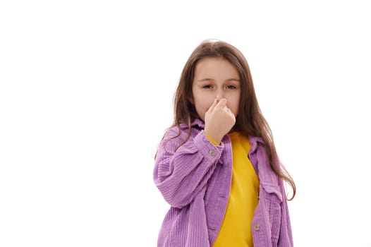Cute Caucasian child girl is closing her nose with her hand, feeling bad from the smell, isolated on white background