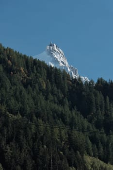 Pic du Midi of Mont-Blanc behind a forest of fir trees
