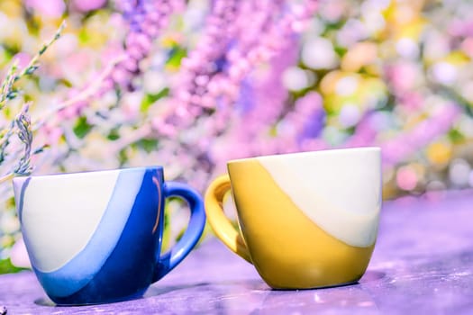 Yellow and blue coffee tea cups on pink floral background