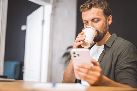 Copywriter focusing on their phone while enjoying cup of coffee home. Concept of working from home is emphasized here, highlighting freedom and flexibility that comes with being self-employed freelancer.