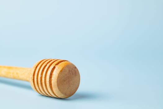 Closeup of a honey dipper on blue background