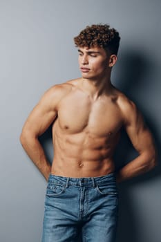 man healthy muscle young naked lifestyle smile bicep guy jeans athletic gray background standing shirtless torso bodybuilder