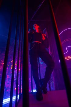 Caucasian woman in neon studio behind steel bars.