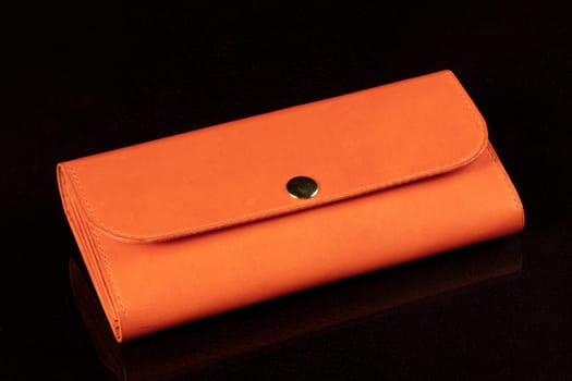 Orange leather wallet on a dark background.