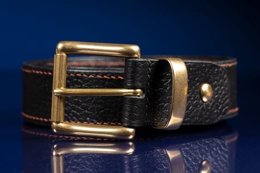 Black leather belt on a dark blue background.