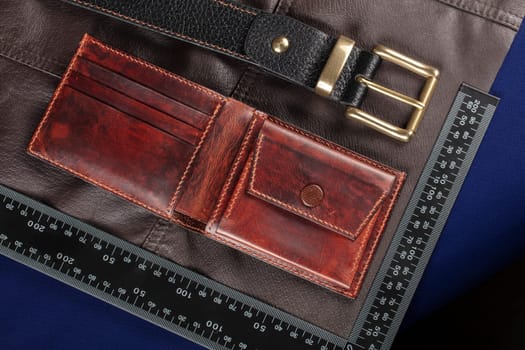 Leather goods purse and belt against the background of a ruler for cutting and sewing.