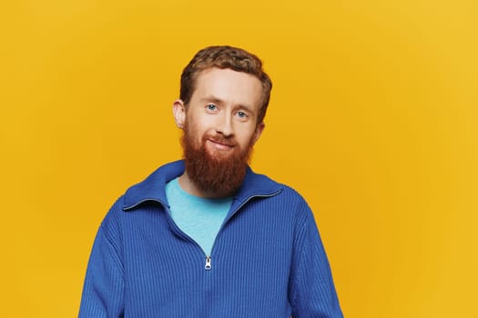 Portrait of a man smiling in a blue sweater on a yellow background copy space, space for text
